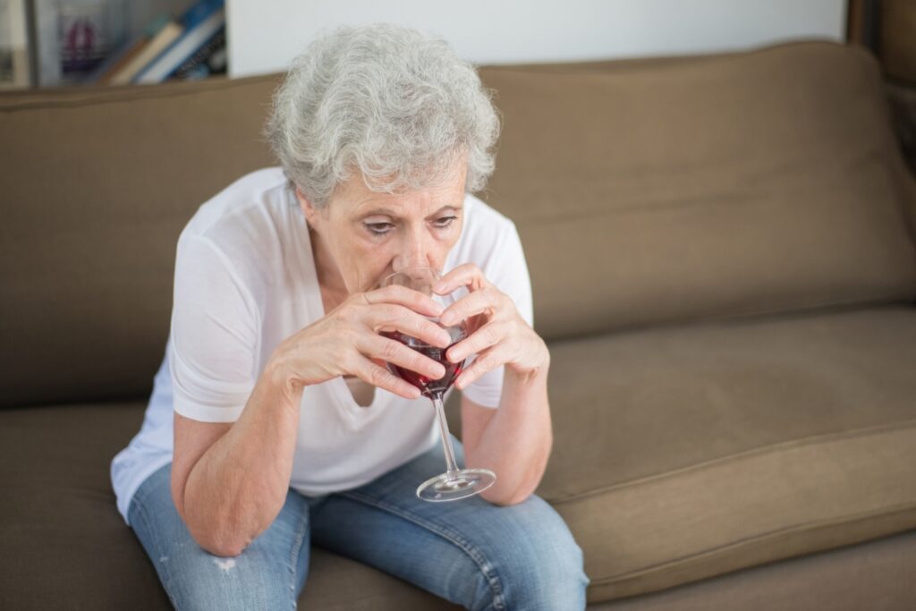 signora anziana alcolista beve in solitudine